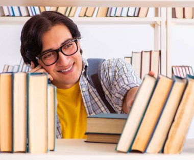 Erkek öğrenci kütüphanede sınava hazırlanıyor.