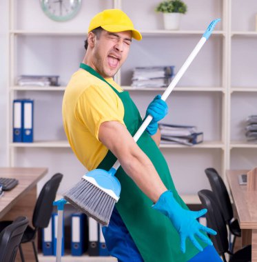 Genç erkek müteahhit ofisi temizliyor.