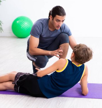 Genç baba ve oğlu egzersiz yapıyor.