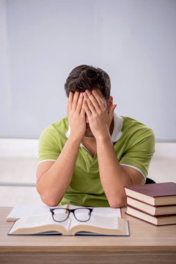 Sınıfta beyaz tahtanın önünde oturan genç öğrenci.