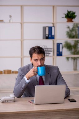 Genç işadamı işyerinde oturuyor.