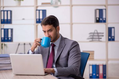 Genç işadamı işyerinde oturuyor.