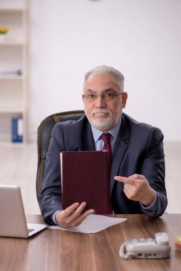 Eski patron ofiste kitap okuyor.