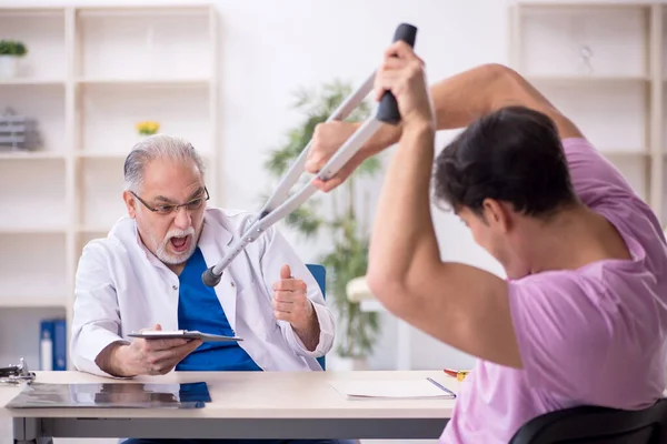 Young Leg Injured Patient Visiting Old Doctor — Stock Photo, Image