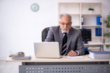 İş yerinde oturan yaşlı erkek çalışan.