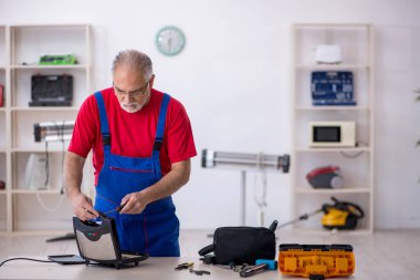 Yaşlı erkek tamirci atölyede sandviç tamircisi tamir ediyor.