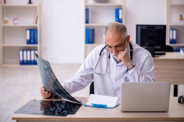 Klinikte çalışan yaşlı erkek radyoloji uzmanı.