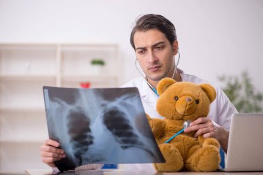 Young doctor holding toy bear clipart