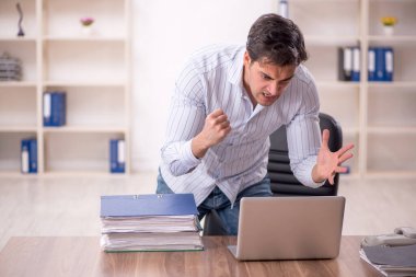 Genç işadamı ve işyerinde çok fazla iş var.