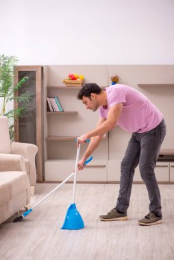 Genç müteahhit evi temizliyor.