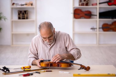 Eski tamirci atölyede müzik aletlerini tamir ediyor.