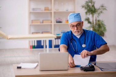 Klinikte çalışan yaşlı bir doktor.