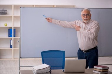 Eski öğretmen beyaz tahtanın önünde.