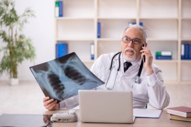 Klinikte çalışan yaşlı erkek radyoloji uzmanı.