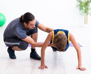 Genç baba ve oğlu egzersiz yapıyor.