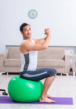 Genç adam evde antrenman ve egzersiz yapıyor.