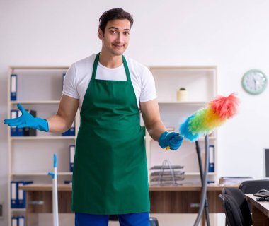 Genç yakışıklı müteahhit ofisi temizliyor.