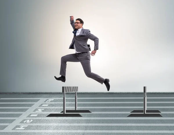 The businessman jumping over barriers in business concept