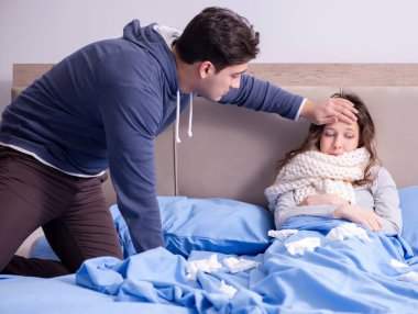 Evde, yatakta hasta kocayla ilgilenen kadın.