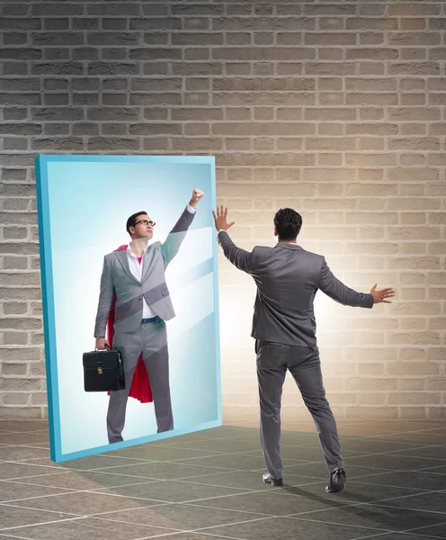 The businessman seeing himself in mirror as superhero