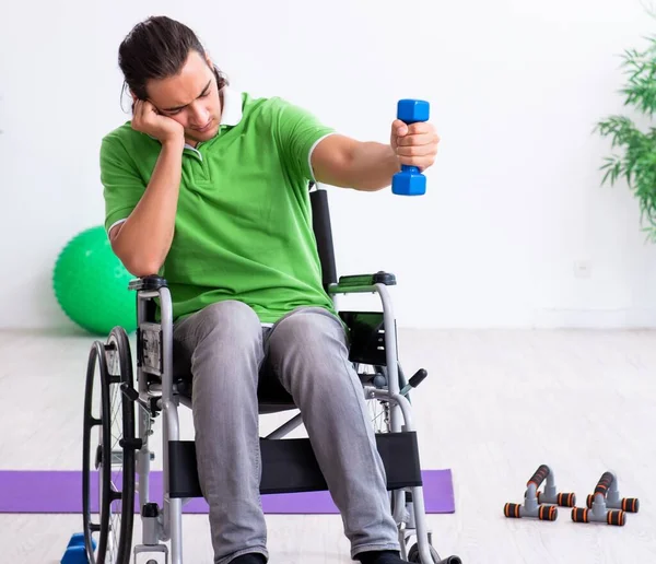 The young man in wheel-chair doing exercises indoors