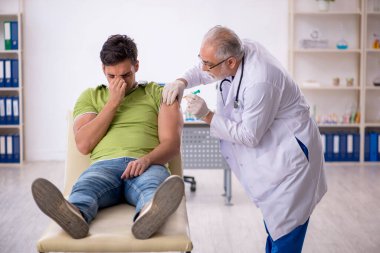 Genç hasta aşı konseptinde yaşlı doktoru ziyaret ediyor.