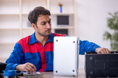 Atölyede bilgisayar tamir eden genç bir tamirci.