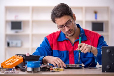 Atölyede bilgisayar tamir eden genç bir tamirci.