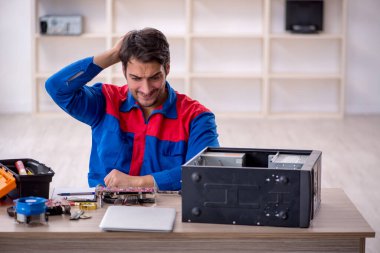 Atölyede bilgisayar tamir eden genç bir tamirci.