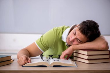 Sınıfta beyaz tahtanın önünde oturan genç öğrenci.