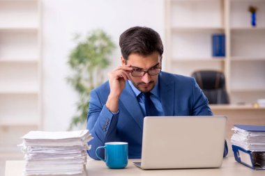 Genç işadamı ve işyerinde çok fazla iş var.