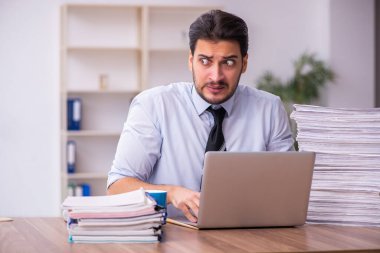 Ofisteki aşırı işten memnun olmayan genç bir erkek işçi.