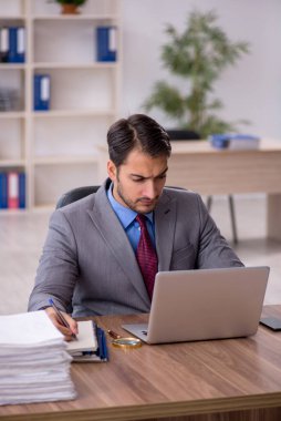 Genç işadamı işyerinde oturuyor.