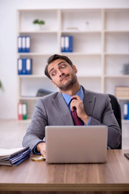 Genç işadamı işyerinde oturuyor.