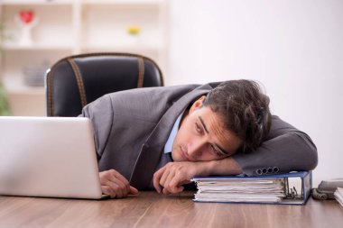 Genç işadamı işyerinde oturuyor.