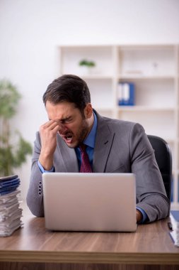 Genç işadamı işyerinde oturuyor.