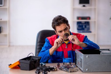 Atölyede bilgisayar tamir eden genç bir tamirci.