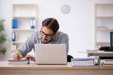 Genç erkek çalışan işyerinde oturuyor.