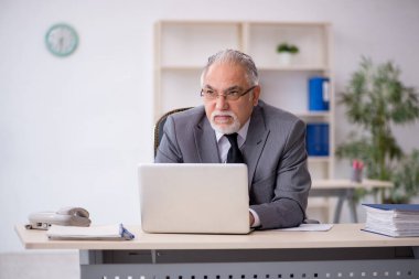 İş yerinde oturan yaşlı erkek çalışan.