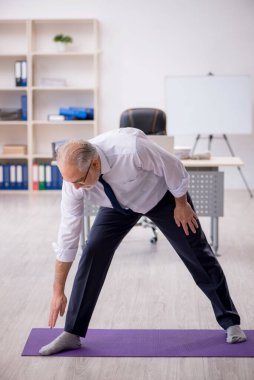 Eski erkek çalışanın teneffüste spor egzersizleri yapıyor.