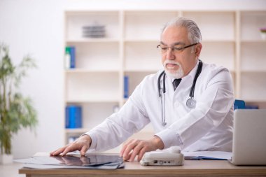 Klinikte çalışan yaşlı erkek radyoloji uzmanı.