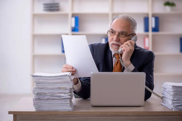 Old businessman employee unhappy with excessive work in the office