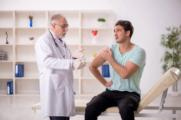 若い患者は予防接種の概念で古い男性医師を訪問 — ストック写真