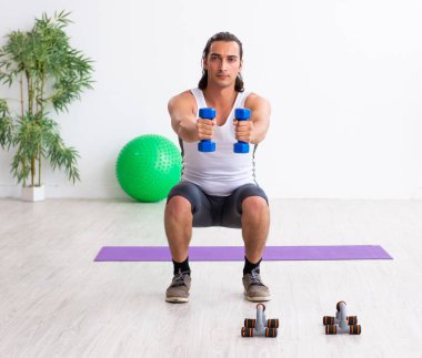 Genç yakışıklı adam içeride spor egzersizleri yapıyor.