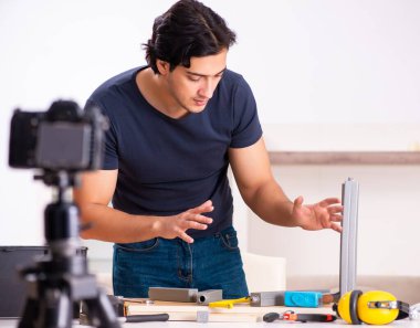 The young male repairman recording video for his blog clipart