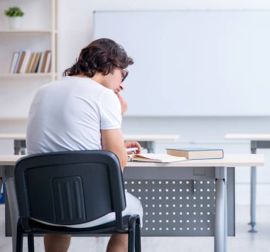 Beyaz tahtanın önündeki genç erkek öğrenci.