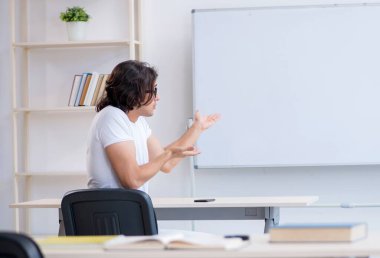 Beyaz tahtanın önündeki genç erkek öğrenci.