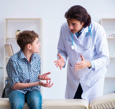 Genç doktor düzenli kontrol için okul çocuğunu muayene ediyor.