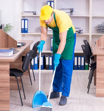 Genç erkek müteahhit ofisi temizliyor.