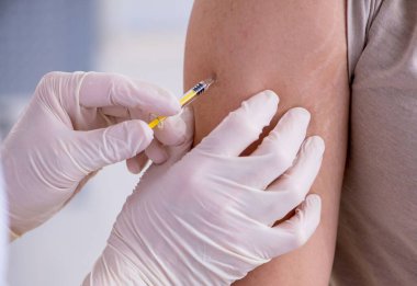 Erkek hasta aşı aşısı için doktoru ziyaret ediyor.